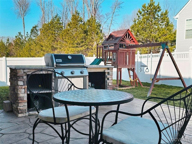 view of patio featuring a playground, fence, and grilling area