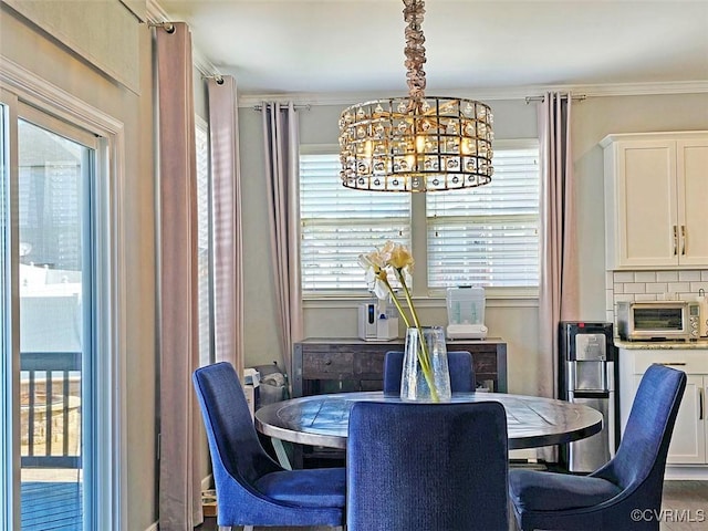 dining area with a toaster, crown molding, and an inviting chandelier