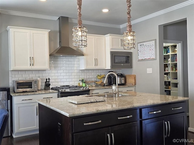 kitchen featuring a sink, stainless steel appliances, wall chimney exhaust hood, and white cabinetry