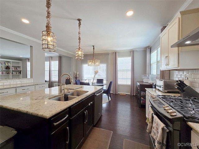 kitchen with a kitchen island with sink, a sink, decorative backsplash, appliances with stainless steel finishes, and crown molding