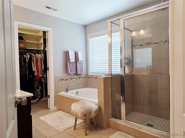 full bath with visible vents, a shower stall, a spacious closet, tile patterned floors, and a bath