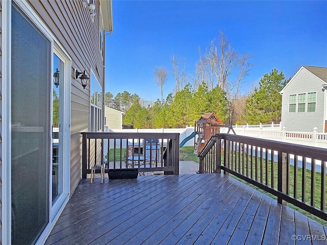 deck with a fenced backyard and a playground