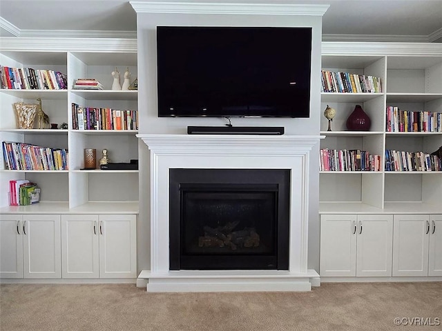 living area featuring light carpet, a fireplace, built in shelves, and ornamental molding