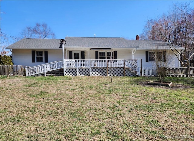 back of property with a lawn, covered porch, a chimney, and fence