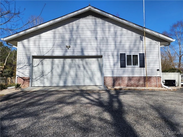 view of property exterior with aphalt driveway, an attached garage, and fence