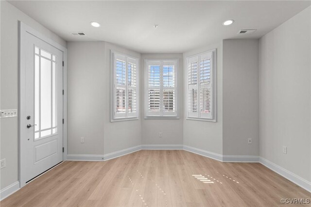 entryway with visible vents, light wood-style flooring, and baseboards