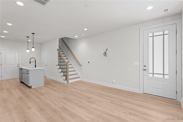 foyer entrance with visible vents, light wood-style floors, and stairs