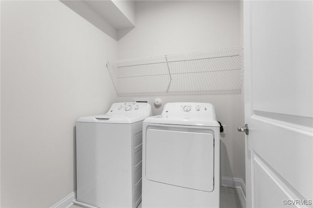 laundry area with laundry area, washing machine and dryer, and baseboards