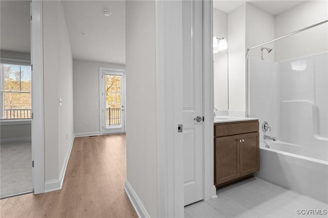 bathroom featuring washtub / shower combination, vanity, baseboards, and wood finished floors