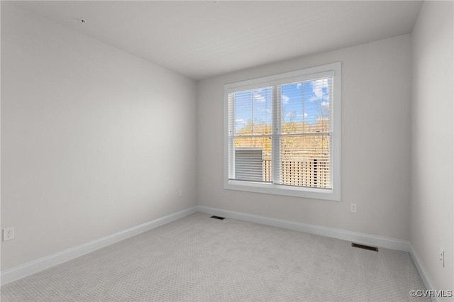 spare room featuring baseboards, visible vents, and light carpet