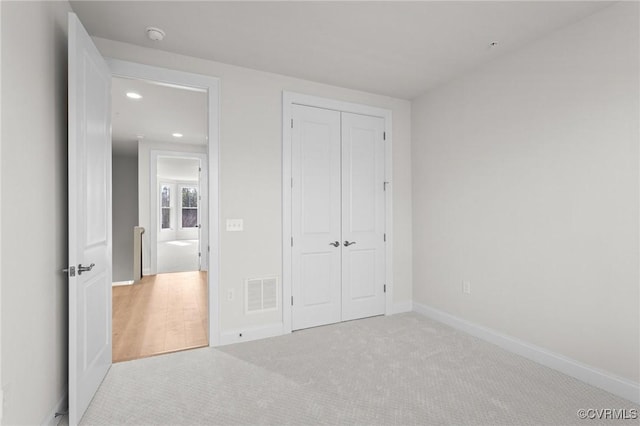 unfurnished bedroom featuring a closet, visible vents, baseboards, and carpet