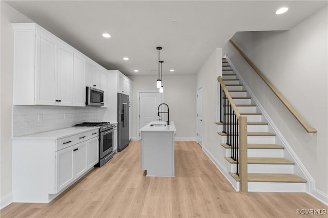 kitchen featuring light wood-style flooring, white cabinets, high end appliances, and a sink