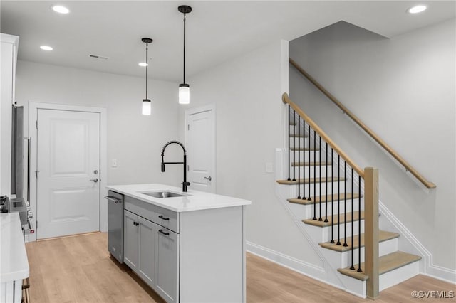 kitchen featuring dishwasher, light wood-type flooring, gray cabinets, and a sink