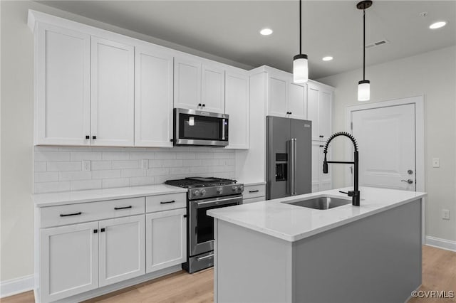 kitchen with visible vents, light wood-type flooring, white cabinets, stainless steel appliances, and a sink