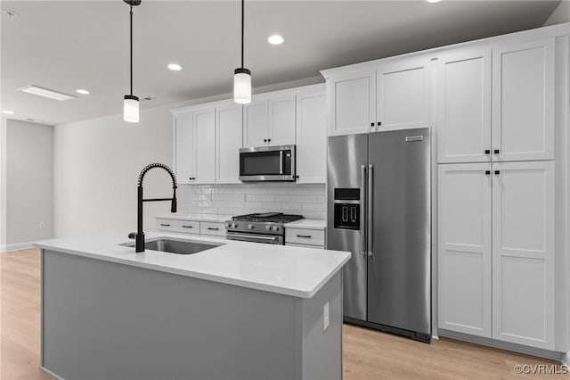 kitchen with a sink, stainless steel appliances, white cabinets, light wood-style floors, and tasteful backsplash