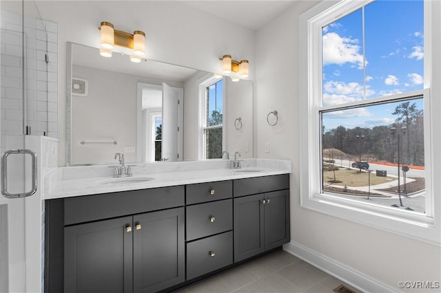 bathroom featuring tile patterned flooring, double vanity, baseboards, and a sink