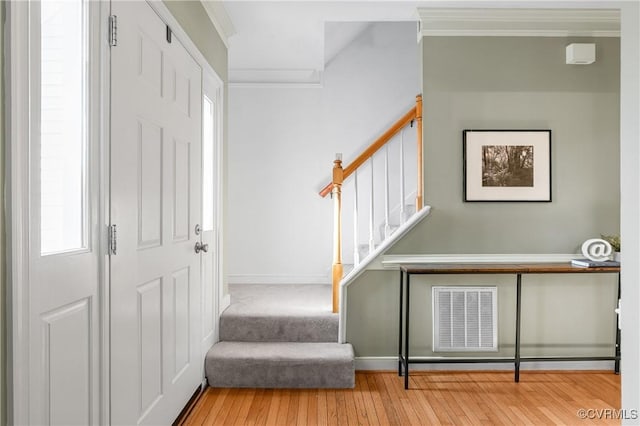 entryway featuring stairway, visible vents, baseboards, hardwood / wood-style flooring, and crown molding