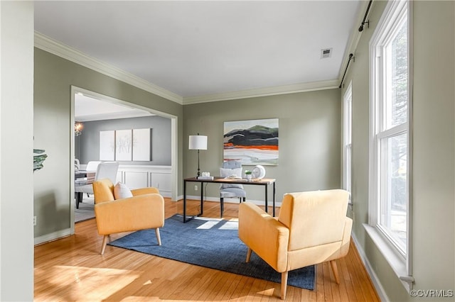 sitting room with visible vents, a healthy amount of sunlight, ornamental molding, and wood finished floors