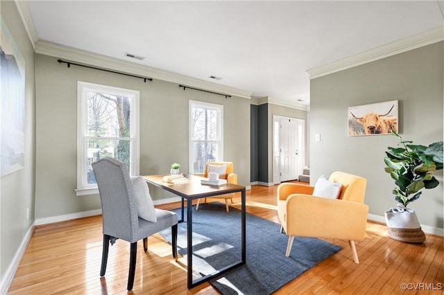 dining room with light wood finished floors, visible vents, and crown molding