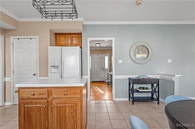 kitchen featuring crown molding, white refrigerator with ice dispenser, light countertops, and light tile patterned floors