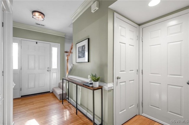 entryway with visible vents, light wood-style flooring, and crown molding