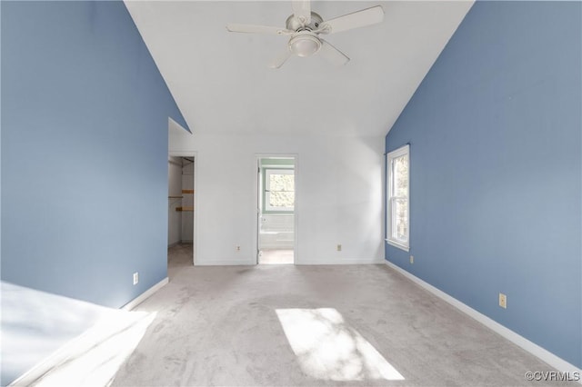 unfurnished bedroom with a walk in closet, baseboards, carpet, ensuite bathroom, and high vaulted ceiling