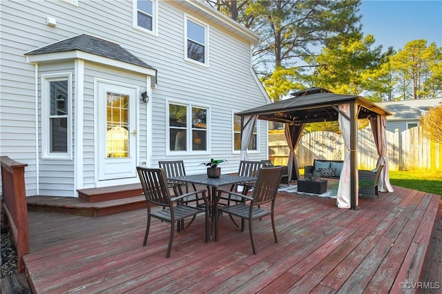 wooden terrace featuring a gazebo, outdoor dining space, and fence