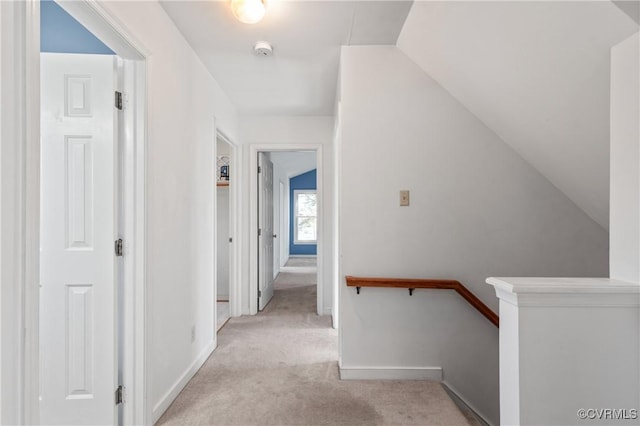 corridor featuring baseboards, light carpet, an upstairs landing, and vaulted ceiling