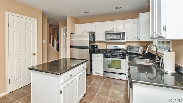 kitchen featuring a center island, dark stone countertops, white cabinets, stainless steel appliances, and a sink