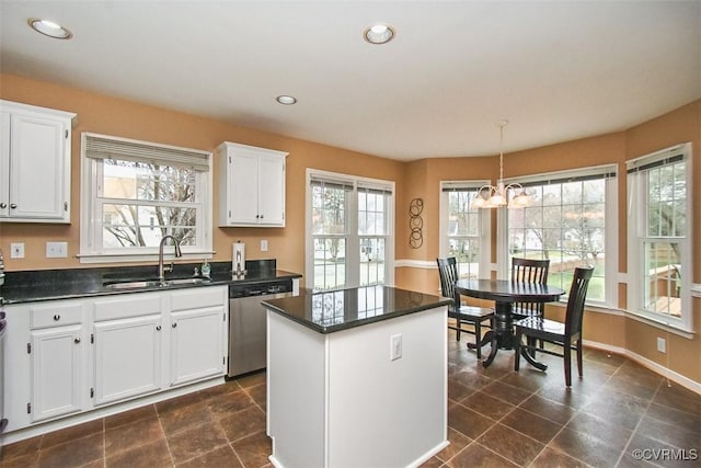 kitchen featuring stainless steel dishwasher, white cabinets, a center island, and a sink