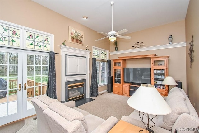 living room with visible vents, a fireplace with flush hearth, light carpet, french doors, and a ceiling fan