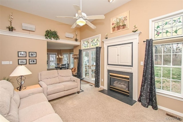 carpeted living area with a fireplace with flush hearth, visible vents, a ceiling fan, and baseboards