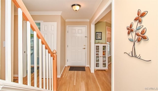 entrance foyer featuring stairway, baseboards, crown molding, and light wood finished floors