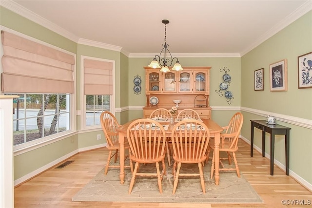 dining room featuring baseboards, visible vents, light wood finished floors, and a chandelier