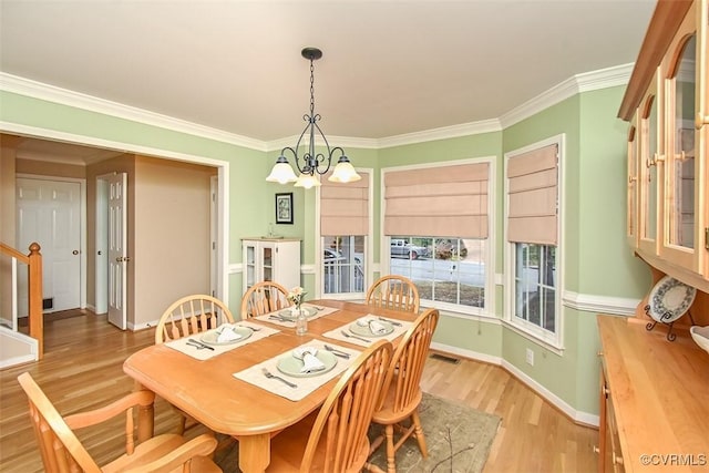 dining space featuring light wood-type flooring, visible vents, ornamental molding, an inviting chandelier, and baseboards