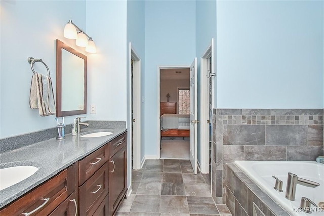 ensuite bathroom with a sink, connected bathroom, double vanity, and tiled bath