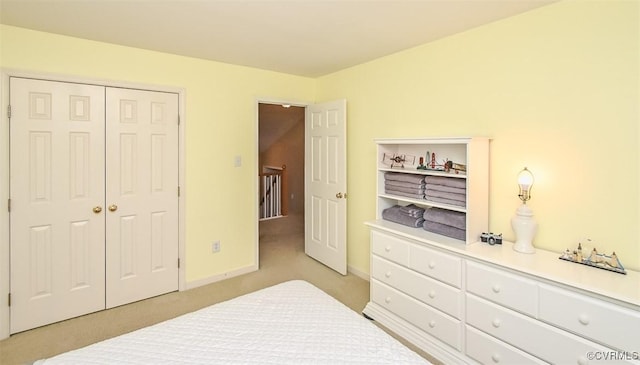 bedroom with a closet, light colored carpet, and baseboards