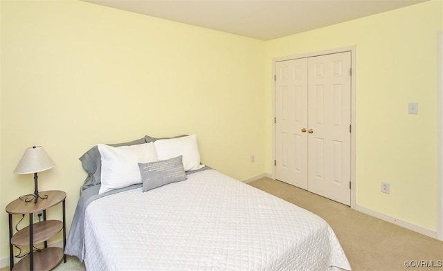 bedroom with a closet, light colored carpet, and baseboards