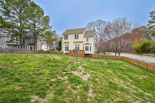 rear view of property with a deck, a yard, and fence