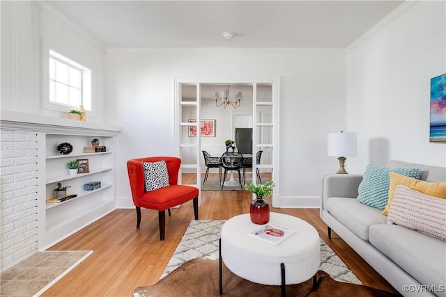 living area featuring a chandelier, baseboards, light wood-style flooring, and crown molding