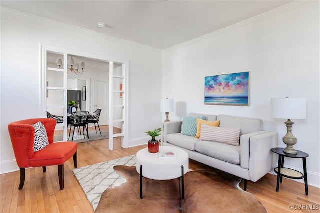 living area with an inviting chandelier, baseboards, crown molding, and light wood-style floors