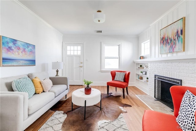 living area featuring a fireplace, crown molding, wood finished floors, and visible vents