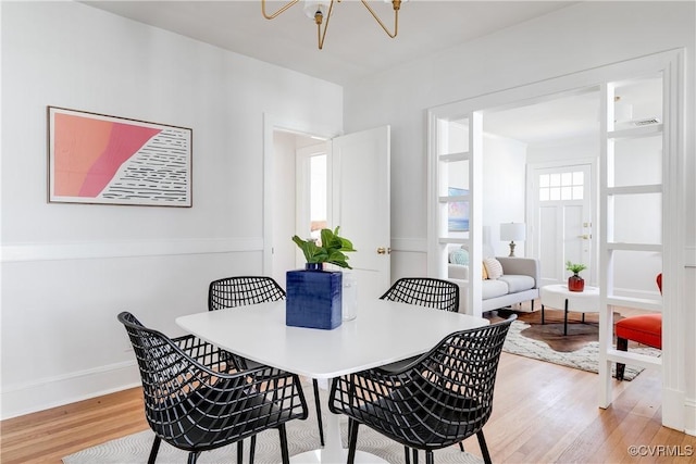 dining room with a chandelier, baseboards, and light wood-style flooring