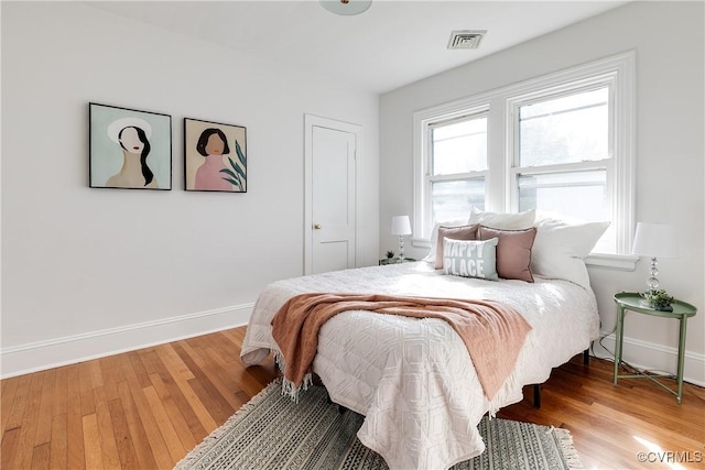 bedroom with light wood-type flooring, visible vents, and baseboards