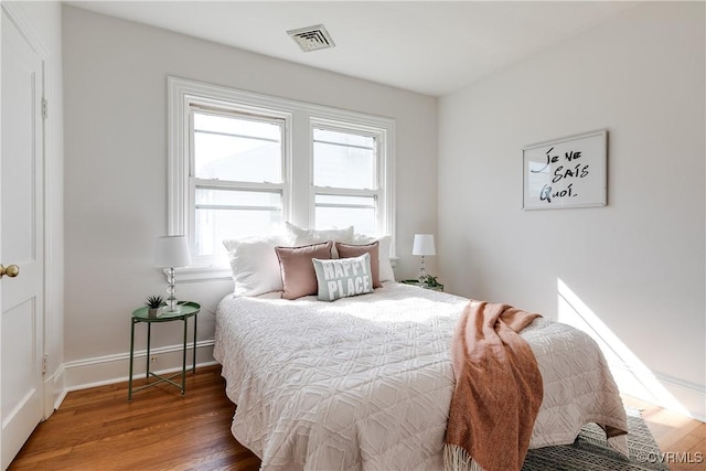 bedroom featuring visible vents, baseboards, and wood finished floors