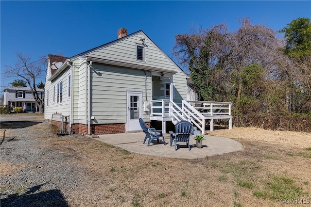 rear view of property with a deck, a chimney, and a patio area