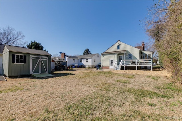 back of property with a storage unit, an outbuilding, a lawn, a deck, and board and batten siding