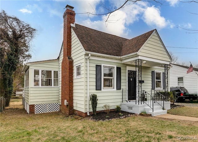 view of front of home featuring a chimney, roof with shingles, a front lawn, and fence