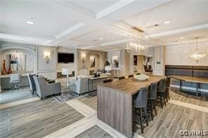 kitchen with a notable chandelier, wood finished floors, ornamental molding, and coffered ceiling