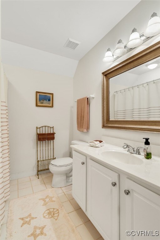 bathroom featuring tile patterned floors, visible vents, toilet, vanity, and vaulted ceiling